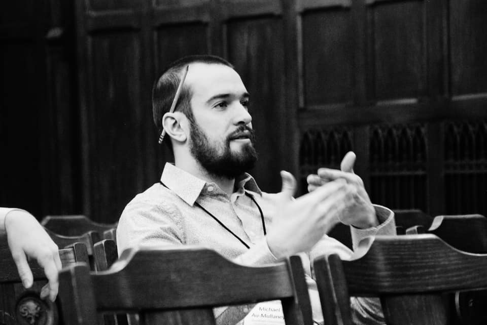 Black and white photo of Michael Au-Mullaney seated at a philosophy conference